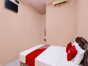 1 dormitorio con 1 cama con manta roja y blanca en OYO 92459 Cahyo Kost 2 en Semarang