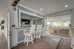 a room with a bar with white chairs and a kitchen at Bayfront Jamaica Beach House Canal Access and Decks in Galveston