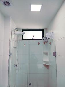 a white bathroom with a shower and a window at Home Boa Viagem in Recife