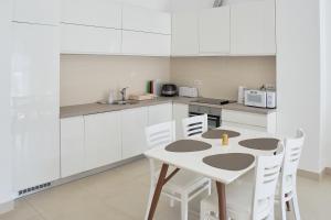 a kitchen with white cabinets and a table and chairs at Lavander Bay C03 in Kotor