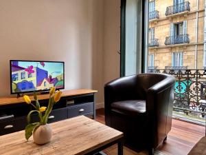 een woonkamer met een stoel, een tafel en een televisie bij Larramendi City Center in San Sebastian