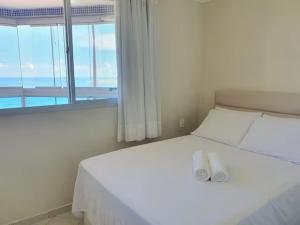 Cette chambre comprend un lit blanc et une grande fenêtre. dans l'établissement Apartamento Completo Frente Praia de Itaparica, à Vila Velha