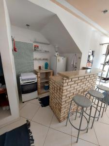 a kitchen with two chairs and a counter with a refrigerator at Arraial Flats in Arraial do Cabo