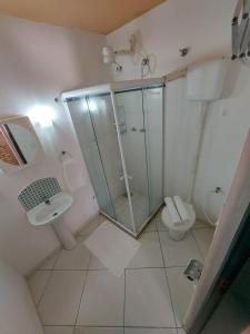 y baño con ducha de cristal y aseo. en Arraial Flats, en Arraial do Cabo