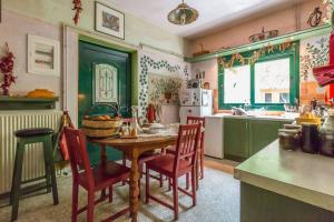 una cocina con mesa de madera y sillas y una cocina con armarios verdes. en Nano's House, en Kala Nera