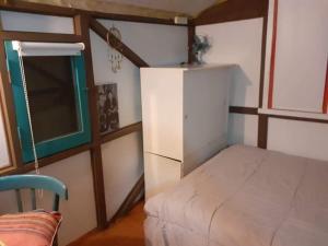 Kleines Zimmer mit einem Bett und einem Kühlschrank. in der Unterkunft Casa Vagón en las sierras in Tandil