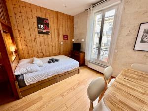 Schlafzimmer mit einem Bett, einem Tisch und einem Fenster in der Unterkunft Le Woody, Centre-ville, Parking gratuit in Bordeaux