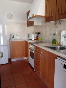 a kitchen with wooden cabinets and a white stove top oven at Alojamentos Vitinho 2 - Vila Nova Milfontes in Vila Nova de Milfontes