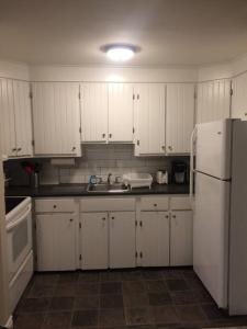 uma cozinha com armários brancos e um frigorífico branco em Bauer Terrace - Cozy 1 bedroom beside The Citadel em Halifax