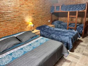 a bedroom with two beds and a brick wall at Cabañas las brisas in La Banda