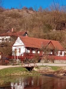 un edificio blanco con techo rojo junto a un lago en Forrásvölgy vendégház, en Jósvafő