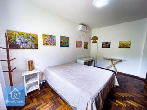 a bedroom with a bed and paintings on the wall at Apartamento completo em frente ao Farol da Barra in Salvador