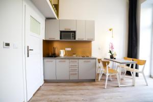 una cocina con armarios blancos y una mesa con sillas. en CracWoW Saint Sebastian Apartments, en Cracovia