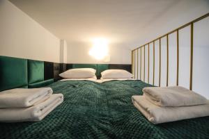 1 cama grande con manta verde y almohadas en CracWoW Saint Sebastian Apartments, en Cracovia