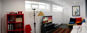 a living room with a television and a red book shelf at Lab Hostel Nazare in Nazaré