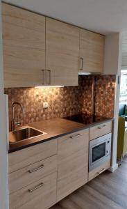 a kitchen with wooden cabinets and a sink and a microwave at Vakantiehuis Jade in Bruinisse