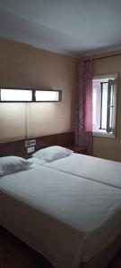 1 dormitorio con 1 cama blanca grande y ventana en Residencial Sol en Portimão