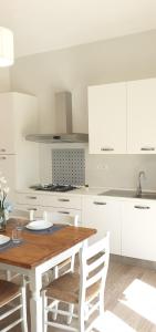 uma cozinha com uma mesa de madeira e armários brancos em Vada al Mare Apartments em Vada