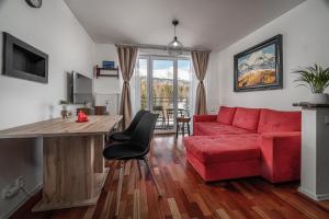 - un salon avec un canapé rouge et une table dans l'établissement Apartman pod Gerlachom s wellness, à Vysoke Tatry - Horny Smokovec