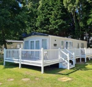 a mobile home with a white fence and trees at Hayley's Holiday Haven in Weeley