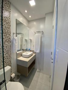 La salle de bains est pourvue d'un lavabo, de toilettes et d'un miroir. dans l'établissement Pousada Bella Casa, à Balneário Camboriú