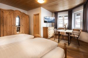 een slaapkamer met 2 bedden, een bureau en een tafel bij Landgasthof Augustiner in Oberstdorf