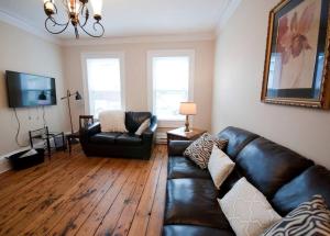 a living room with a leather couch and a television at Heritage Townhouse in Downtown Halifax in Halifax