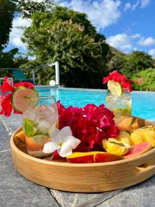 a tray of fruit and flowers on a table next to a pool at La Sucrerie, magnifique villa avec Piscine in Sainte-Anne