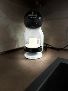 IN MEDIA URBE - intero appartamento في لاكويلا: آلة صنع القهوة مع كوب يجلس على الأرض