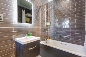 een badkamer met een wastafel, een bad en een spiegel bij The Manor Coastal Hotel & Inn, Blakeney, Norfolk in Blakeney