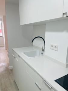 マドリードにあるPisos con Piscina Barrio Exclusivo-MOVISTAR ARENA alquiler temporadaの白いキッチン(シンク、白いキャビネット付)