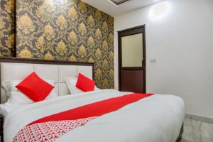 a bedroom with a large white bed with red pillows at OYO Anshun Residency Near M2k Cinemas Rohini in New Delhi