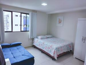 1 dormitorio con 1 cama y 1 sofá azul en Home Boa Viagem, en Recife