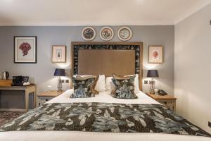 a bedroom with a large bed with three plates on the wall at The Manor Coastal Hotel & Inn, Blakeney - part of The Coaching Inn Group in Blakeney