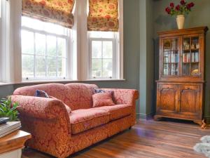 a living room with a pink couch and two windows at The Old Vicarage in Westward