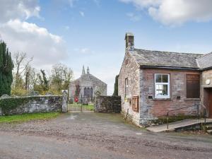an old stone house with a gate and a church at The Old Vicarage in Westward