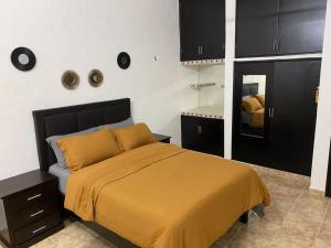 a bedroom with a bed with yellow sheets and a mirror at Casa Leonor. 2 cuartos, 2 baños, Cocina, cochera. in Valladolid