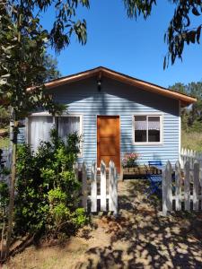 een klein blauw huis met een houten deur en een hek bij cabañas camino al totoral in El Quisco