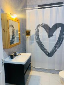 uma casa de banho com um lavatório e um coração desenhado na cortina do chuveiro em Laura's Cozy HOME em Madaba