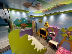 高雄親子溜滑梯High Fun旅店 في كاوشيونغ: غرفة نوم للأطفال مع جدار ديناصور
