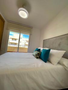 sypialnia z dużym białym łóżkiem z niebieskimi poduszkami w obiekcie Apartamentos Playa Ventilla w mieście Aguadulce