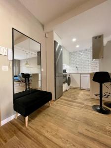 sala de estar con reposapiés negro y cocina en Apartamentos Playa Ventilla, en Aguadulce