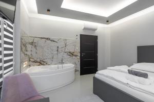 een witte badkamer met een bad en een wastafel bij OŽA apartmány in Ostrava