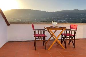 una mesa con 2 sillas y una copa de vino en el balcón en Casa da Agrela, en Ponte da Barca