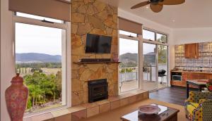 a living room with a stone wall with a fireplace at Panoramia Villas in Myrtleford