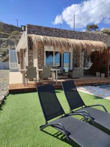 a house with two lawn chairs and a patio at Peace & View in Archangelos