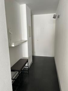 une pièce vide avec un banc et un mur blanc dans l'établissement Appartement Tourbillon centre-ville, à Sion
