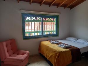 1 dormitorio con 1 cama, 1 silla y 1 ventana en vista piedra, en Guatapé