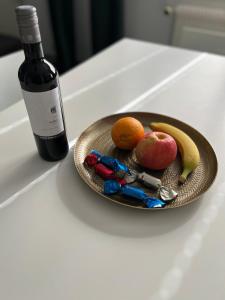 a plate of fruit on a table with a bottle of wine at Appartement Tourbillon centre-ville in Sion