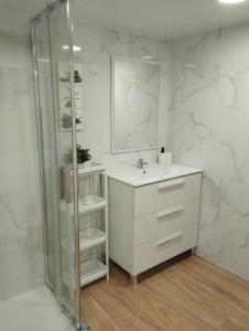 La salle de bains blanche est pourvue d'un lavabo et d'un miroir. dans l'établissement Day Ok Casa Terrasa Beach, à Malgrat de Mar